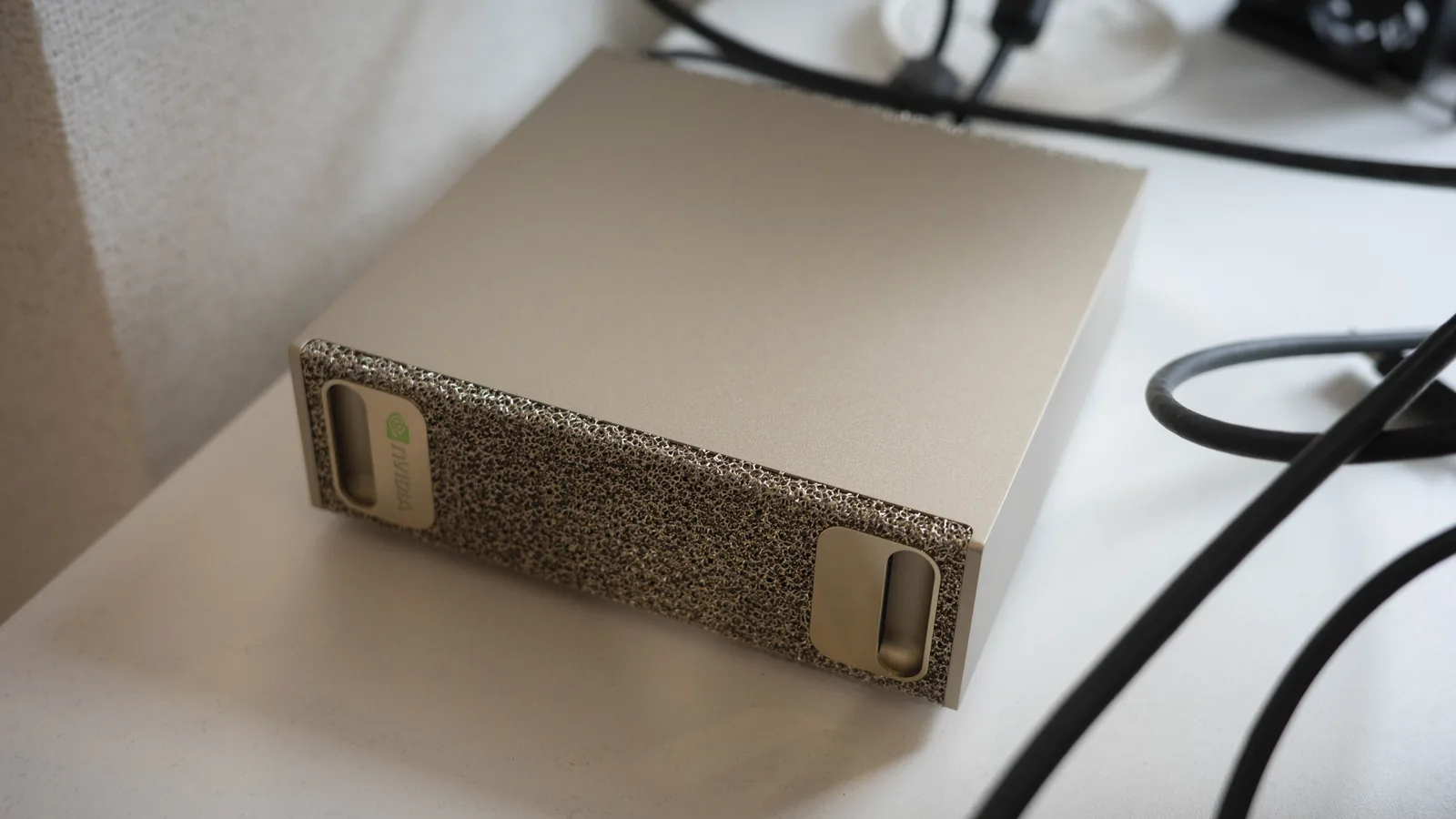 机の上に置いたNVIDIA DGX Spark。前面は金属のフォーム素材で、左右に取っ手がある